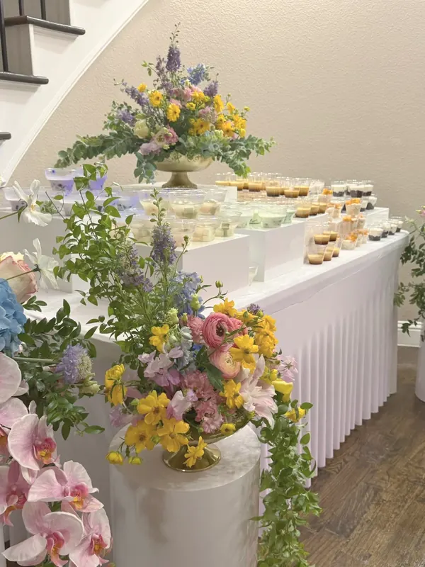 Spring garden florals — ranunculus, delphinium & orchids beside a dessert bar